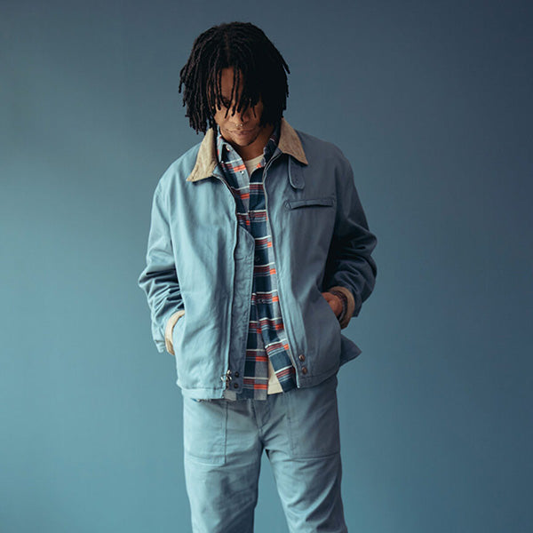 odel wearing the Storm Canoe Club x Engineered Garments Club Coat and matching Fatigue Pants with a plaid shirt