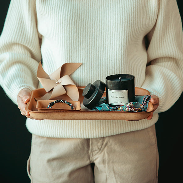 Person in white sweater holding a tray of apothecary goods