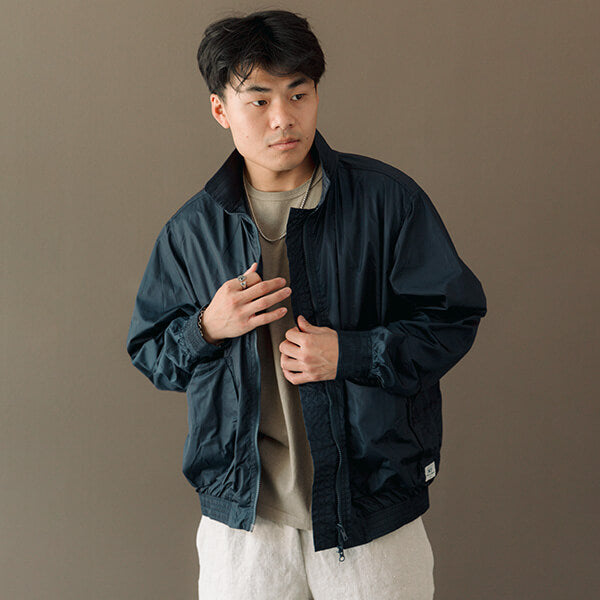 Model wearing navy sassafras jacket, almond t-shirt, natural shorts and white mm6 sneakers. 