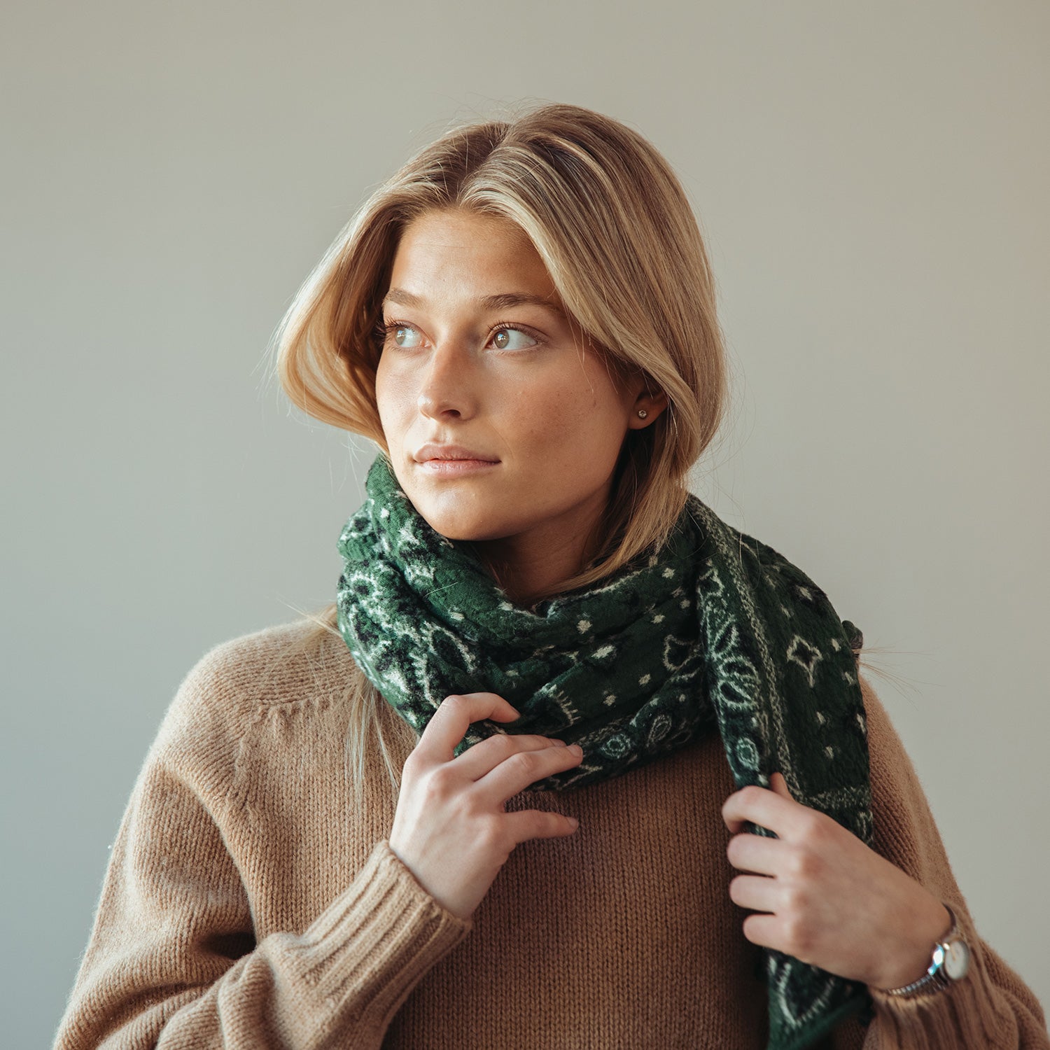 Close up picture of model wearing brown sweater and green kapital scarf featuring a gift guide.