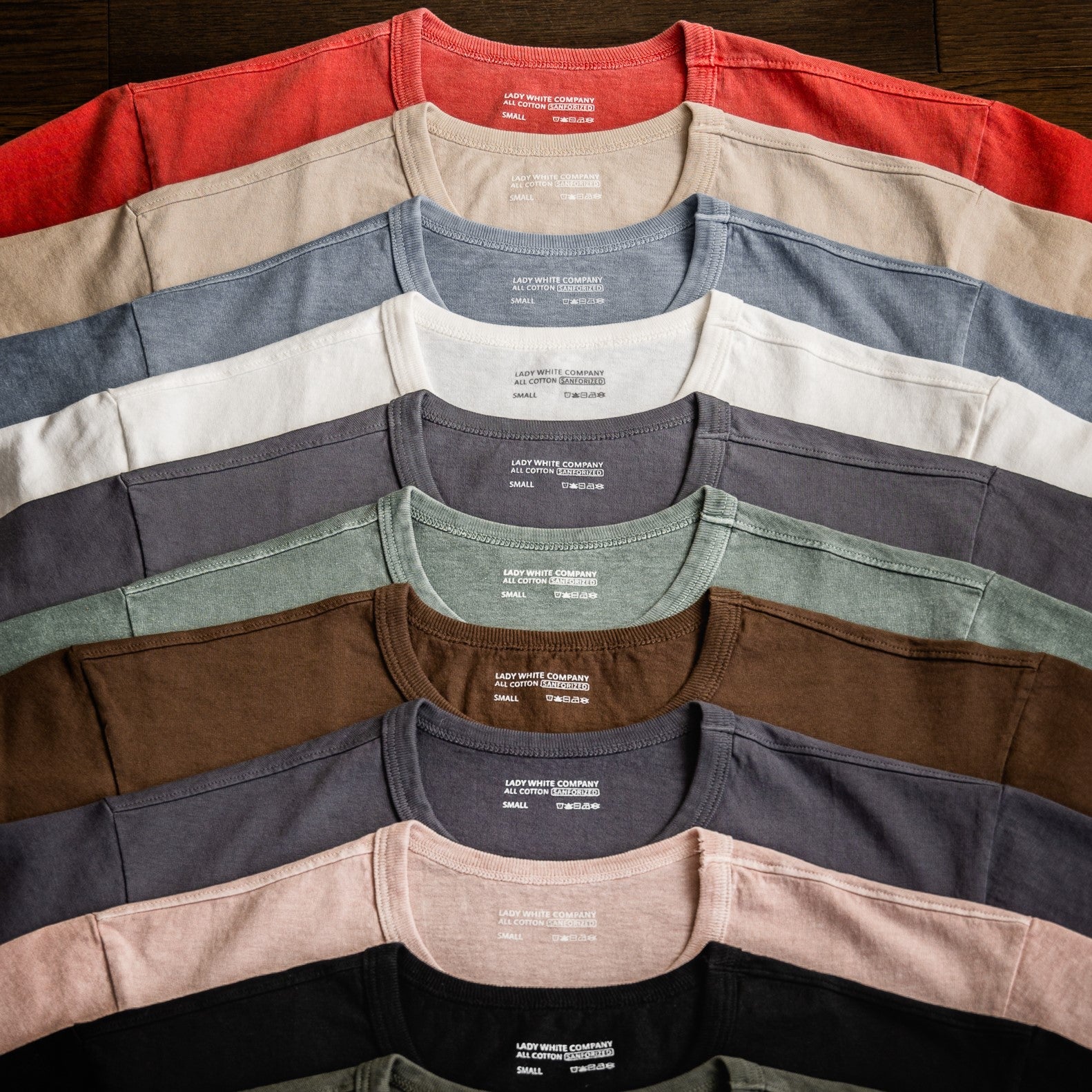 Flat lay of Lady White Co. T-shirts in multiple colors arranged together.