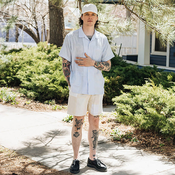 Image of model wearing cap, camp color, and shorts all in light tones